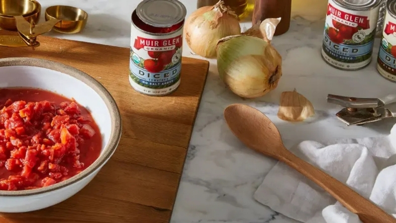 Muir Glen organic tomato products displayed with fresh cooking ingredients